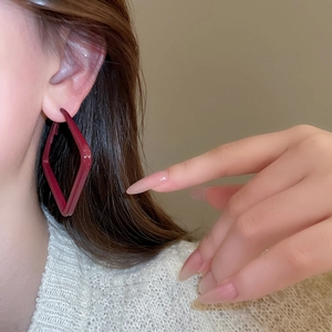 Detailed view of deep red geometric diamond-shaped earrings worn by a model in lifestyle setting