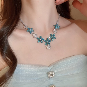 Gros plan d'un collier à pendentif fleur en argent avec zircons bleus porté par un mannequin