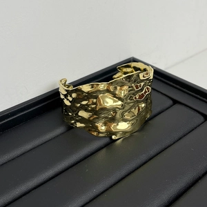 Detailed view of wide golden hammered texture cuff bracelet on a black display tray