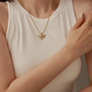 Elegant gold dragonfly necklace with white shell inlay pendant on a model's neck