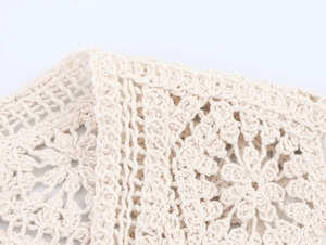 Close-up of beige crochet knit fabric with intricate hollow patterns and geometric lace details