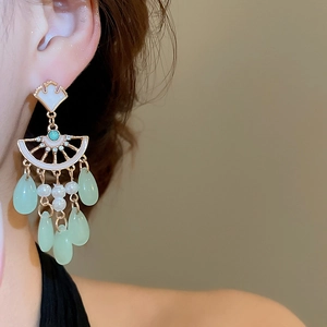 Detailed close-up of vintage ginkgo leaf earrings with tassels and white pearls on model