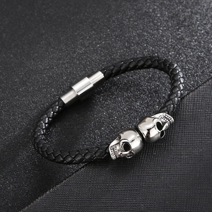 Macro view of black braided leather bracelet with silver skull details and magnetic clasp