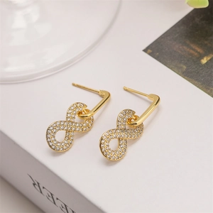 Macro detail of infinity gold earrings featuring pave-set white cubic zirconia stones