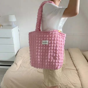 Pink popcorn texture tote bag with LOVE SOZAKKA patch worn by a model in a bedroom