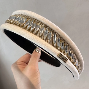 Détail d'un serre-tête en velours beige orné de strass brillants et base en métal doré