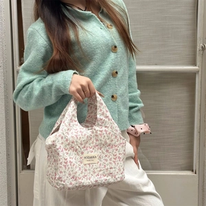 Detailed shot of floral lunch bag with SOZAKKA label held by person in casual outfit