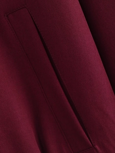 Detail of wine red twill fabric with precision stitching on the pocket of the jacket