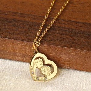 Close-up of 18K gold heart pendant with horse engraving and crystal stone accents