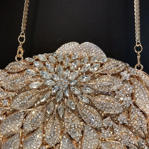 Macro view of golden evening clutch bag with sparkling floral rhinestone patterns and chain