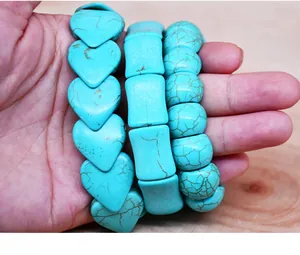 Detail of three turquoise bead bracelets with heart and geometric shapes on a palm