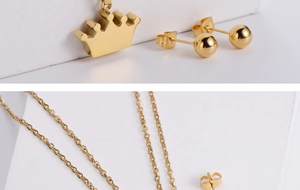Detail of gold crown pendant and ball stud earrings on a minimalist geometric stand
