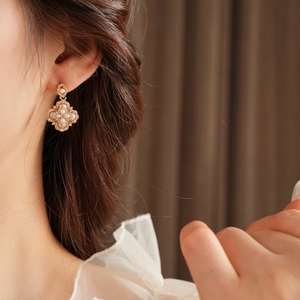 Gros plan de boucles d'oreilles fleurs vintage avec perles et cristaux sur un modèle