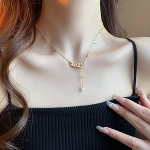 Detail of elegant gold plated necklace featuring enamel flowers and faux pearl drop
