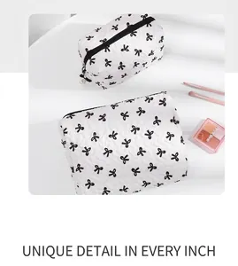Macro detail of quilted makeup bag with black bow pattern and zipper pull detail