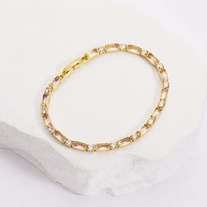 Dettaglio del bracciale dorato con pietre rettangolari rosa e zirconi chiari lucidi