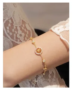 Detailed view of gold compass star pendant bracelet with cubic zirconia on female wrist