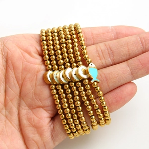 Gold beaded bracelet set with blue fish charm and white shell evil eye heart pendants
