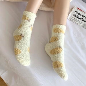 Gros plan de chaussettes douces en polaire corail avec motifs poires sur fond blanc cocooning