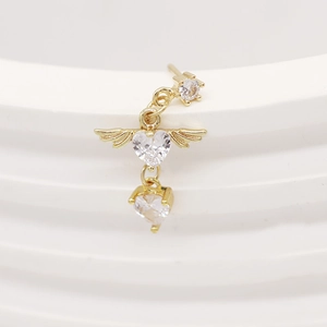 Macro detail of gold L-shaped nose stud featuring heart-shaped zircons and angel wings