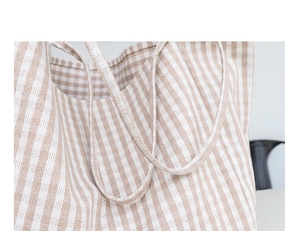 Detailed close-up of beige striped canvas bag stitching and textured fabric handle