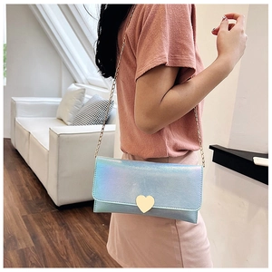 Detail of laser iridescent blue crossbody bag with golden heart buckle and chain strap