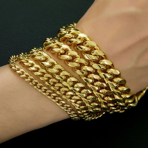 Detail of layered gold 14K plated Cuban link bracelets in various widths on male wrist