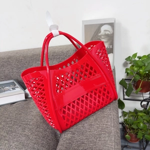 Close-up of a red hollow-out woven jelly tote bag with ergonomic round double handles