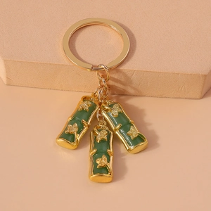 Detail of bamboo joint keychain with emerald imitation jade and gold metal charms
