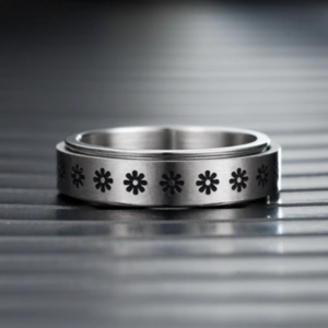 Detalle macro de un anillo giratorio de acero de titanio con flores grabadas.