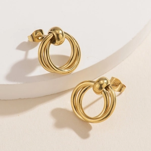 Macro view of triple-link interlocking geometric gold stud earrings on a stone base