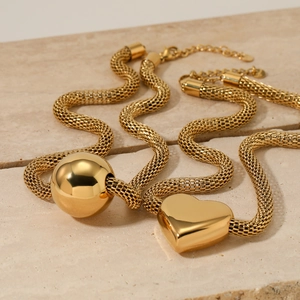 Gold mesh chain necklace set featuring hollow sphere and heart pendants on beige stone