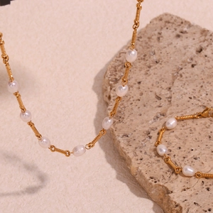 Macro shot of 18K gold plated spiral chain necklace and bracelet with freshwater pearls
