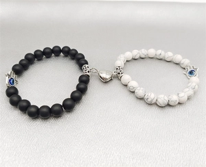 Detail of couple bracelets with heart magnets, Hamsa Hand charms, and natural stones