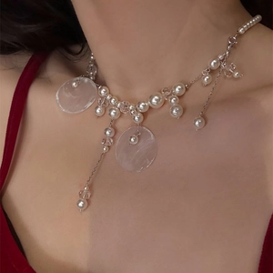 Detail view of pearl and acrylic fringe necklace worn on neck with retro fashion style