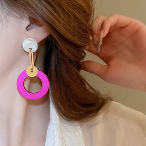 Close-up of geometric earrings with white marble resin and bright fuchsia pendant on model