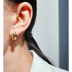 Minimalist gold teardrop stud earring worn by model showing glossy metallic finish