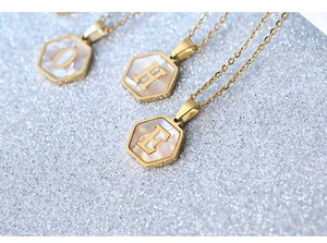 Macro shot of gold hexagon shell pendants with O, H, and E letters on glitter background