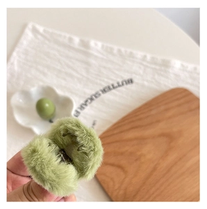 Close-up of green plush hair claw clip showing soft texture and internal structure