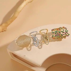Dettaglio di anelli geometrici in zircone oro e argento su un piedistallo beige