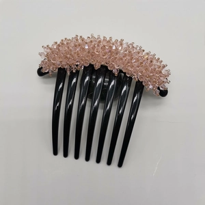 Close-up of pink crystal beads on a seven-tooth black hair comb for elegant updos
