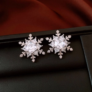 Macro shot of silver snowflake earrings with hexagonal cubic zirconia and black leather