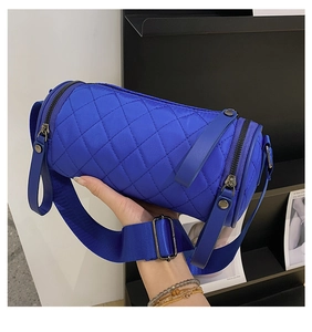Detail of blue quilted cylinder crossbody bag with nylon strap and metal zipper