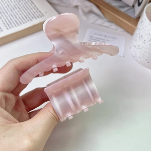 Close-up of pink acetate hair claw clip with pearlescent marble texture and metal spring