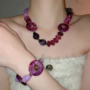 Irregular purple acrylic jewelry set with gradient beads and golden clasp on a model