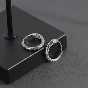 Detailed close-up of vintage silver hoop earrings with intricate snake scale textures