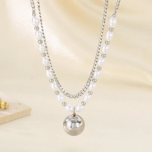 Detail of layered titanium steel necklace with metallic bead and faux pearls over soft cloth