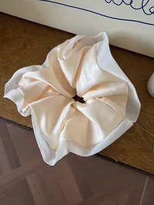 Detail of satin scrunchie with organza trim and smooth beige silk texture on wood