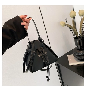 Detail of black triangular punk handbag with silver cross and metallic chain accents