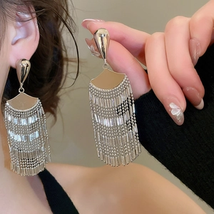 Detail of silver fan-shaped fringe earrings featuring elegant metal chain tassels